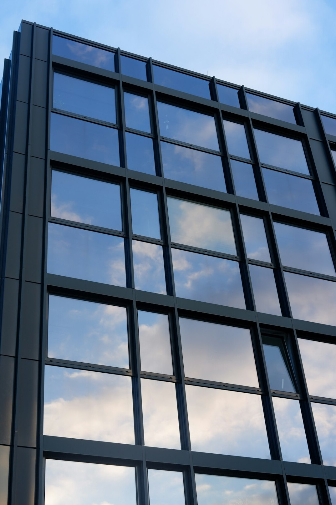 Modern glass office building exterior against a clear sky