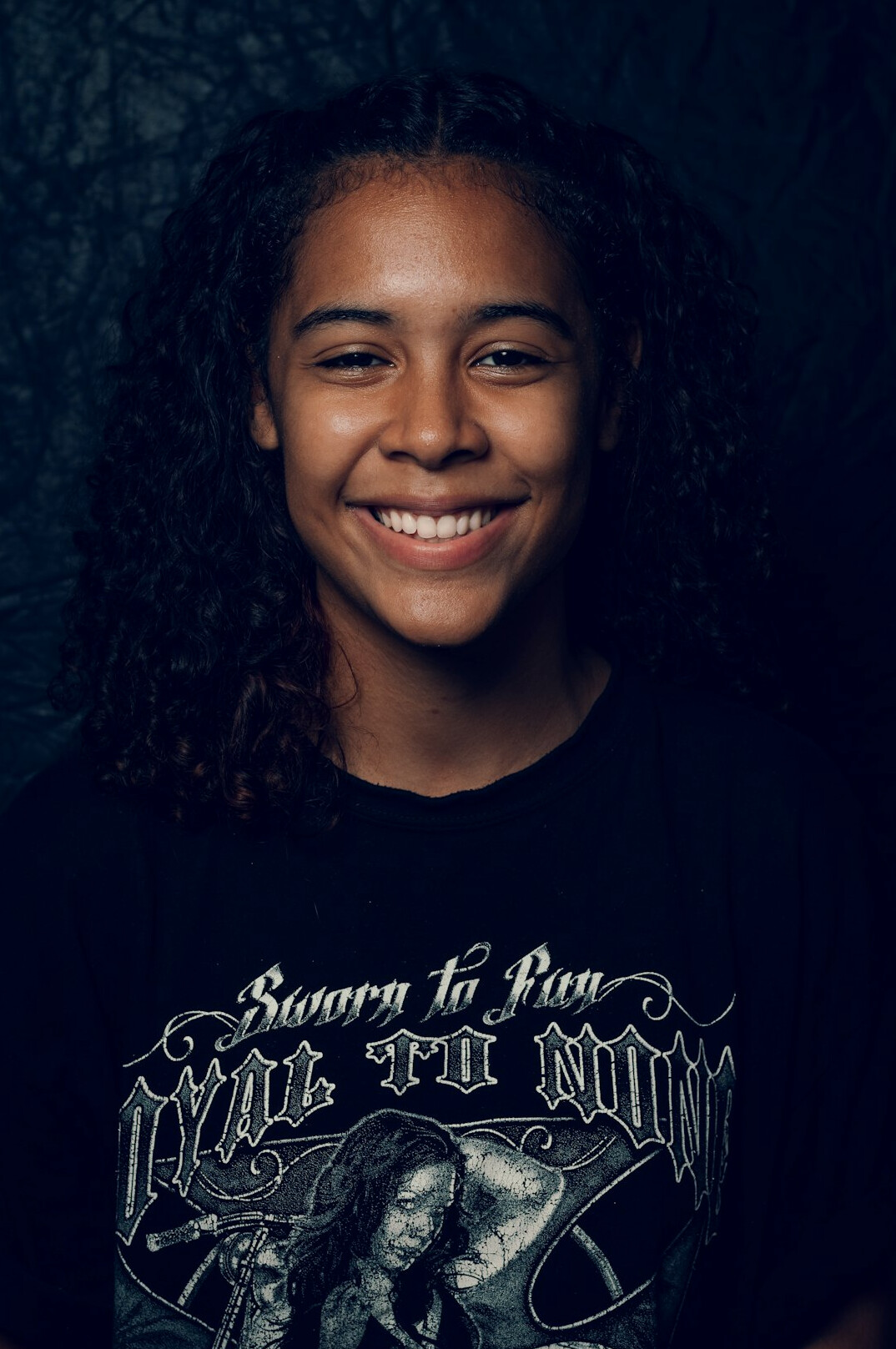 Studio portrait of a young woman with curly dark hair smiling